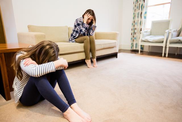 Upset mother and daughter sitting in living room at home