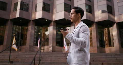 Businessman Focused on Smartphone Outside Corporate Building