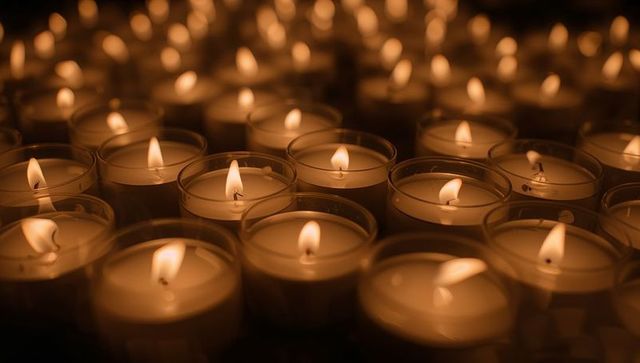 Rows of flickering votive candles in glass holders casting warm sanctuary glow