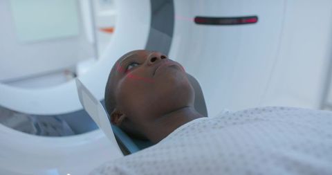 African woman undergoing ct scan with red laser alignment in hospital radiology department