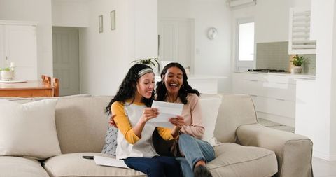 Happy Women Reading Letter Together in Cozy Living Room