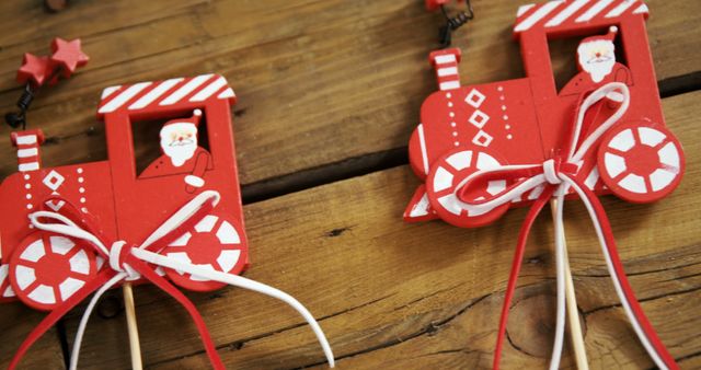 Red and white wooden Christmas decorations shaped like a train and sleigh rest on a wooden surface, with copy space. These festive ornaments evoke the holiday spirit and traditional Christmas decor.