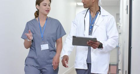 Healthcare Team Walking and Discussing Patient Care in Hospital Corridor with Tablet