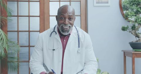 Confident Doctor Smiling With Pen in Study