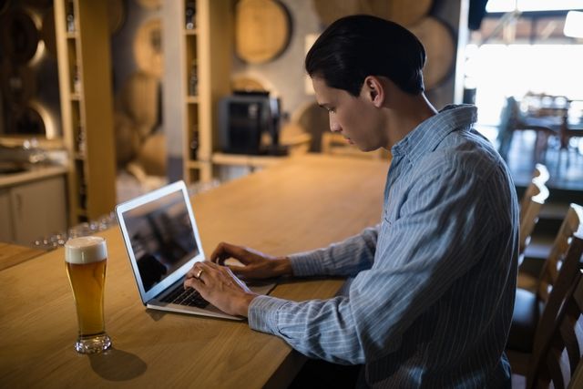 Man using laptop while having beer - Download Free Stock Photos Pikwizard.com