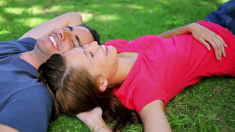 Happy Couple Relaxing on Grass in Park Setting