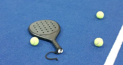 Padel racket on blue court with tennis balls