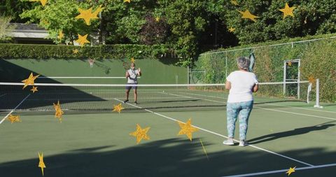 Senior woman playing tennis with partner on sunny outdoor hardcourt