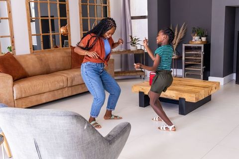 African american mother and daughter dancing in modern sunlit living room bonding moment