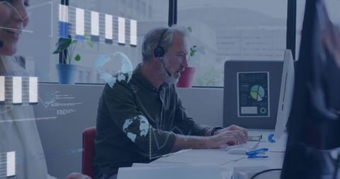 Silver-haired it support specialist wearing headset working at desktop with analytics dashboards