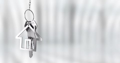 Hanging house keyring with keys and metallic house charm on soft blurred background