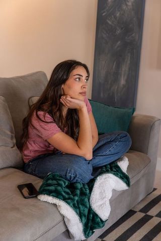 Young woman sitting cross-legged contemplating in cozy living room