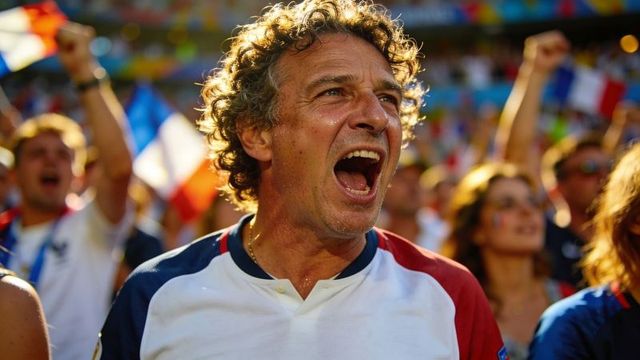 Middle-aged man cheering passionately in stadium during soccer match with tricolor flags