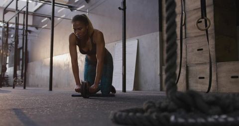 Confident woman with ab roller in industrial gym setting