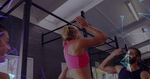 Woman performing pull-up on gym rig with spotter boosting strength and teamwork