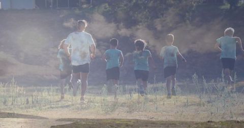 Coach and Youth Group Running in Dusty Field Embracing Outdoor Fitness