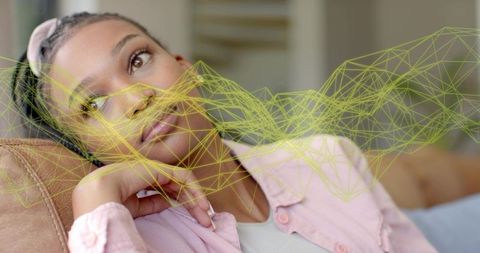 Young woman reclining on sofa with augmented reality wireframe visualization overlay