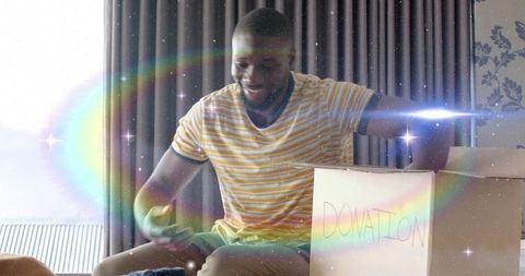 Packing donation box with joyful smile and sunlit lensflare in cozy living room