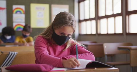 Girl in Classroom Wearing Facemask Writing in Notebook - Download Free Stock Images Pikwizard.com