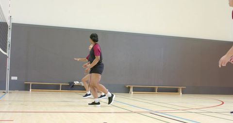 African american athlete leading volleyball drill on indoor court with teammates in motion