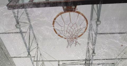 Vintage basketball hoop with weathered rim and frayed net in gymnasium atmosphere