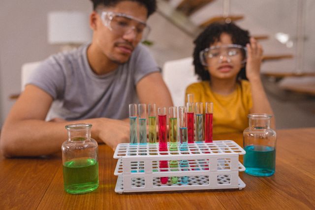 Hispanic father and son looking at chemical solutions in test tubes and beakers. unaltered, family, science experiment, discovery and learning concept.