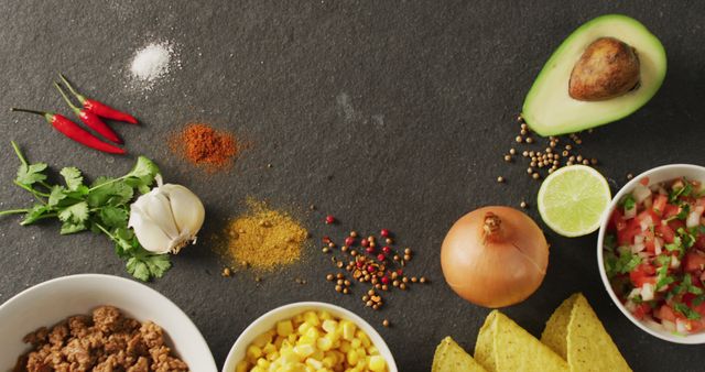 Image of tacos, salad, meat lemon, spices and other ingredients lying on black background. cuisine, cooking, food preparing, taste and flavour concept.