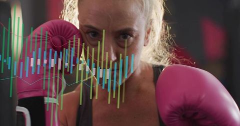 Female boxer training with pink gloves and digital fitness data overlay in boxing gym