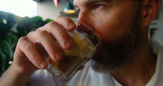 Man drinking coffee in a cozy café closeup. This image captures the essence of relaxation and enjoyment, perfect for use in marketing materials for coffee shops, advertisements for beverages, lifestyle blogs, or social media posts about morning routines.