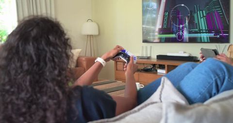 Couple relaxing on couch playing console games together in cozy modern living room