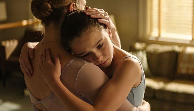 Ballet teacher embracing comforting teenage dancer during emotional studio rehearsal