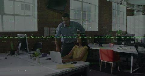 Business team collaborating over laptop in modern industrial office with data overlay