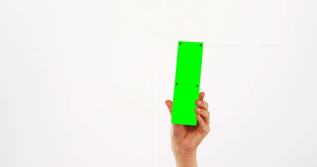 Hand is holding smartphone with green screen for concept of technology or app promotion. Ideal for demonstrations, presentations, marketing materials, and digital product showcases. The green screen allows easy editing for adding custom content.