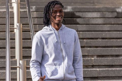 Smiling african american man leaning on handrail on urban concrete steps in gray hoodie