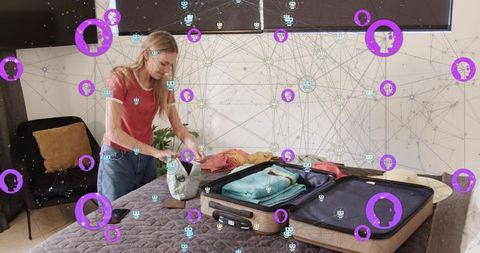 Young woman packing suitcase on bed with augmented reality network overlay and smartphone