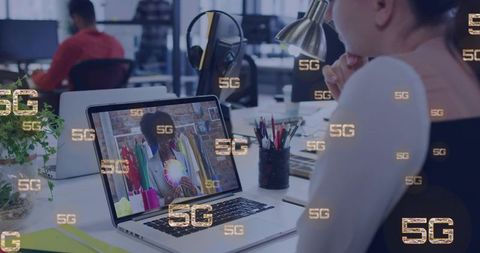 Creative team reviewing color palette over 5g video call on laptop in modern workspace