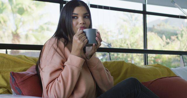 Image of happy biracial woman sitting on sofa and drinking coffee - Download Free Stock Photos Pikwizard.com