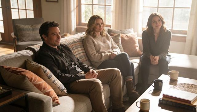 Three adults sitting on sunlit couch sharing warm conversation over coffee in cozy living room