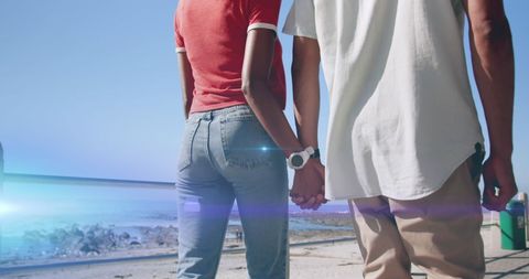 Couple Holding Hands Walking by Beachside on Sunny Day