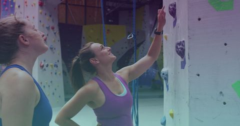 Fit Women Strategizing Wall Climbing Inside Gym