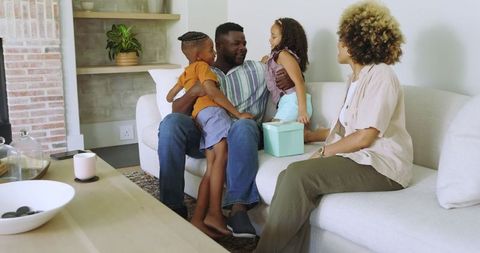 Loving Family Sharing Gift Time at Home on Cozy Sofa