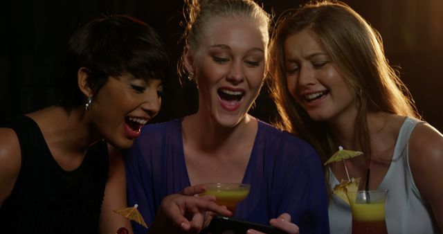 Women Enjoying Night Out Laughing and Looking at Smartphone - Download Free Stock Images Pikwizard.com