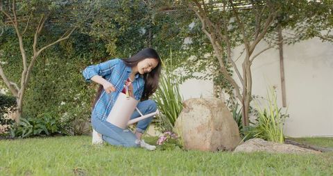 Woman watering flower garden in peaceful summer backyard