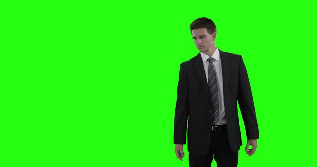 A young Caucasian businessman stands confidently against a green screen background, with copy space. His professional attire and posture suggest readiness for a corporate environment or advertisement placement.