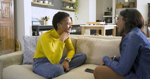 Female friends laughing and bonding in cozy living room
