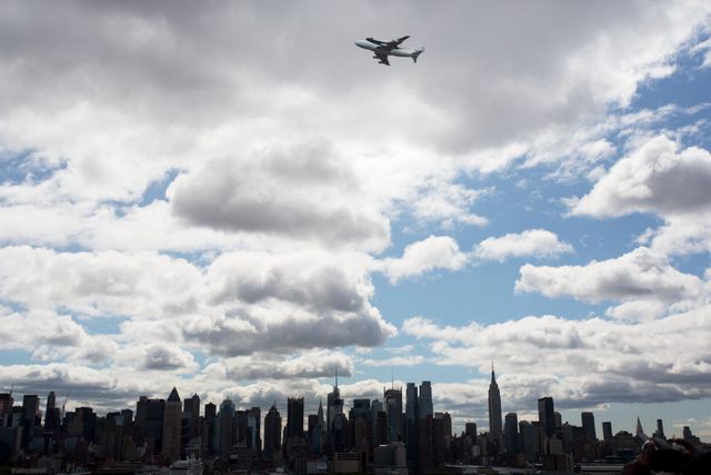 Space Shuttle Enterprise mounted atop NASA 747, flies over New York skyline on April 27, 2012. This historic image captures a significant moment in space and aviation history. Ideal for educational materials, historical documentaries, aviation and space program promotions, and New York City tourism content.