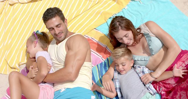 Happy caucasian family lying on towels at beach and playing. Vacation, free time, summer and family.