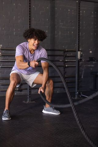 African american man swinging battle ropes in industrial gym for strength and endurance training