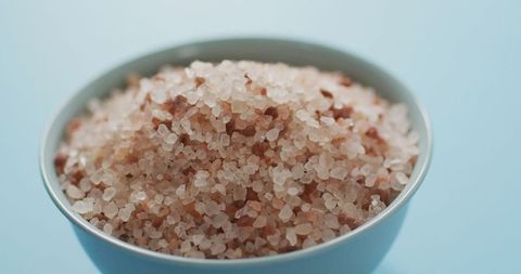 Himalayan pink salt in ceramic bowl on light blue background