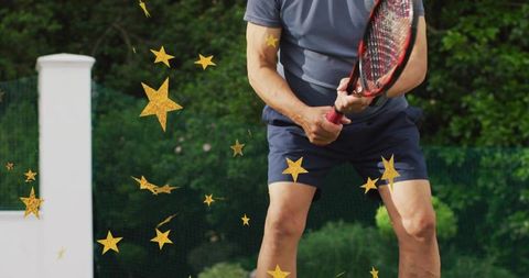 Senior man playing tennis on outdoor court holding racket with golden star overlays